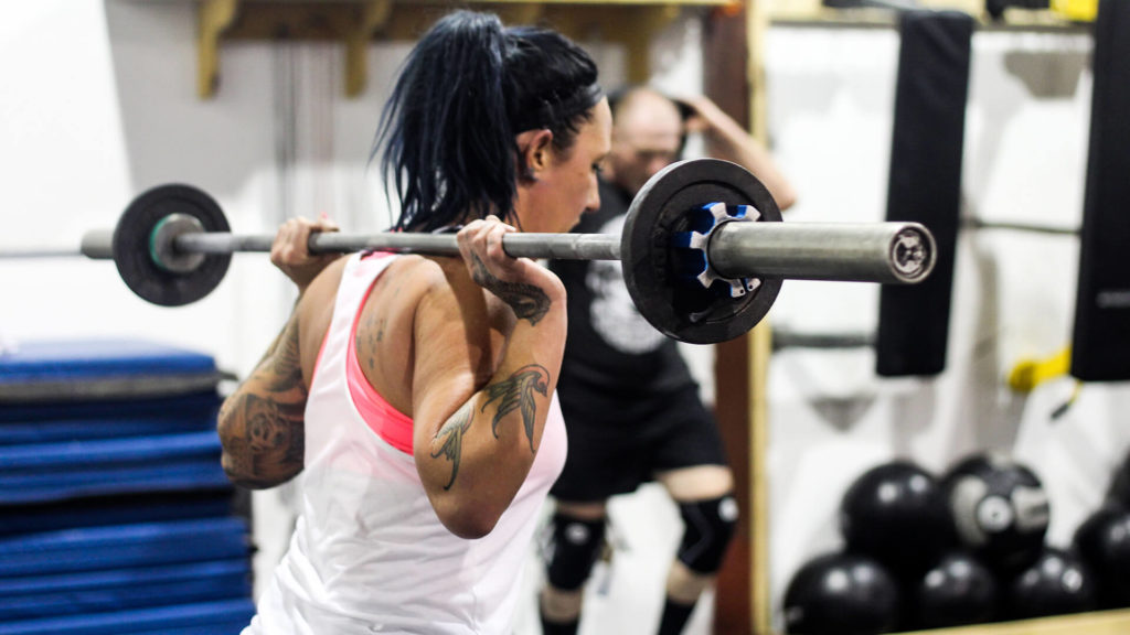 woman holding a barbell behind her head
