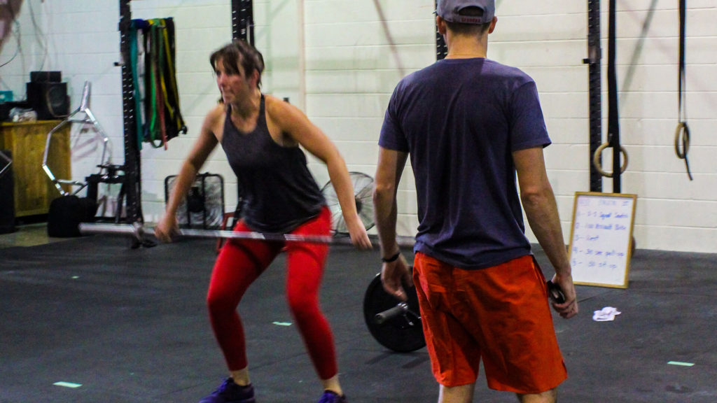 crossfit coach evaluating woman doing a clean